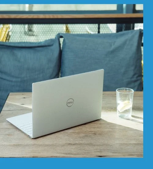 Dell laptop on a wooden table with the back of the display facing the camera.